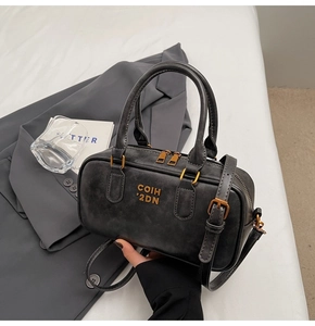 Detailed shot of dark grey Boston bag with gold logo and adjustable shoulder strap