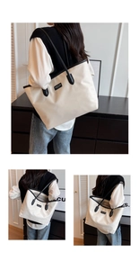 Detail of a large beige nylon tote bag with black leather straps and brand label