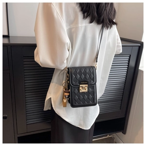 Detail of black quilted crossbody phone bag with gold lock and cute bear charm