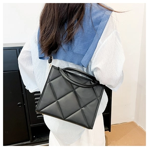 Detail of classic black quilted crossbody bag with golden hardware and round handle