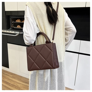 Detail of dark brown quilted tote bag showing rhombus stitching and texture