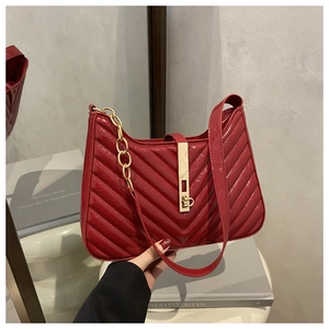Détail d'un sac à bandoulière en cuir verni rouge foncé avec matelassage en V et boucle dorée