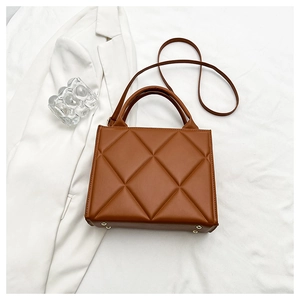 Close-up of brown quilted faux leather bag with metal rivets and adjustable shoulder strap