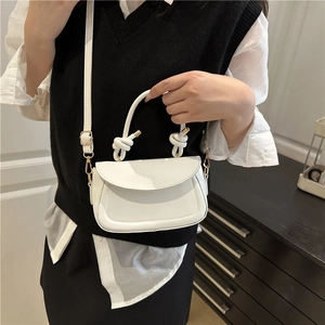 White French retro saddle bag with knotted handle and gold buckle worn by a woman