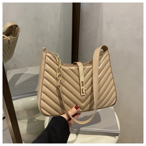 Détail du sac sous le bras beige brillant avec surpiqûres en V et boucle en métal doré