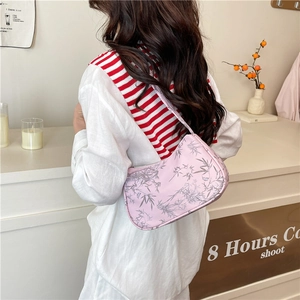 Pink underarm bag with grey bamboo leaf print worn by a model in a minimalist room