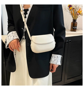 Detailed view of a white minimalist saddle bag worn by a model in a modern interior