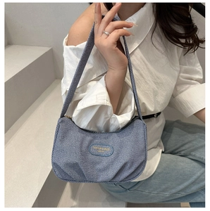 Dettaglio della borsa hobo in denim a righe bianche e blu con etichetta logo sul davanti