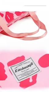 Detailed close-up of pink yoga bag featuring red lip prints and a woven brand label