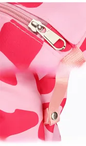 Detail of metal zipper and side snap button on pink camouflage travel bag with webbed strap