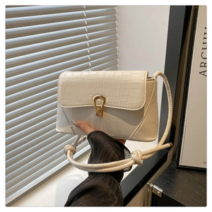 Detailed view of cream crocodile-texture handbag with elegant gold U-shaped metal buckle