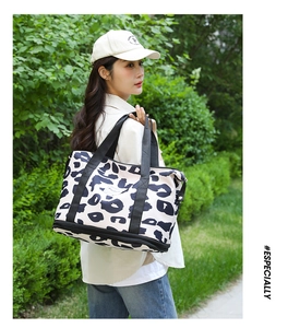 Outdoor view of a black and white leopard print tote bag with adjustable shoulder strap
