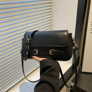 Chic black contrast crossbody bag with gold buckles and acrylic chain on leather texture