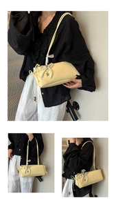 Detail der cremefarbenen Schultertasche mit großer Perlen-Schleife und Herz-Anhänger