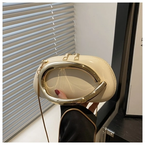 Detail of cream white leather bag featuring a large U-shaped gold hardware and chain strap