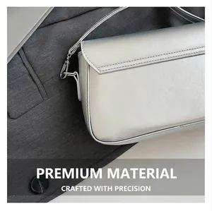Détail macro du cuir argenté et des coutures soignées sur un sac à bandoulière minimaliste