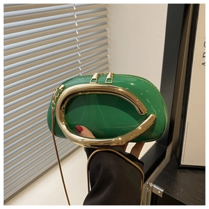 Detail of bright green patent leather clutch with a large gold oval metal handle and chain