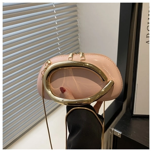 Detail of pink acrylic shell bag featuring a thick gold metal handle and chain strap