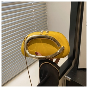 Detail of glossy yellow patent leather bag with bold gold semi-circular metal handle