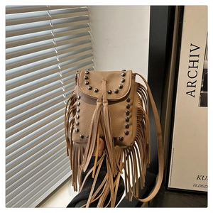 Detalle de mini bolso de cuero caqui con remaches metálicos y flecos largos decorativos