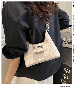 Detailed view of beige woven texture and metal bow clasp on minimalist shoulder bag