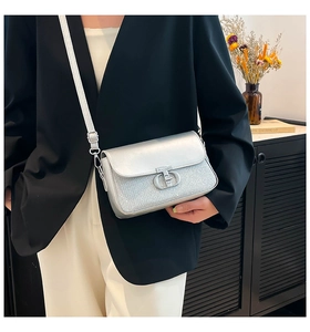 Détail du sac bandoulière argenté avec paillettes et boucle métallique porté par un mannequin