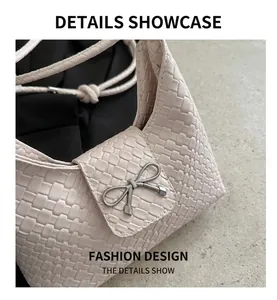 Détail de la texture en cuir tressé et boucle nœud en métal argenté sur le sac à main crème