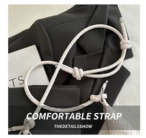 Détail de la bandoulière en cuir tressé crème avec nœud décoratif et boucle en métal