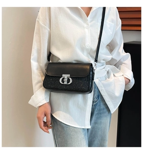 Détail du sac bandoulière noir pailleté avec serrure en T argentée sur un modèle