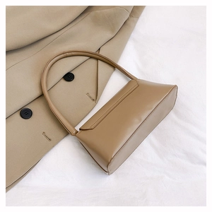 Gros plan détaillé d'un sac baguette en cuir beige sur un manteau en laine élégant
