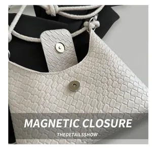 Gros plan sur la boucle magnétique argentée du sac à main en cuir blanc tressé