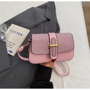 Detailed close-up of pink shoulder bag with glitter texture and gold H-shaped clasp