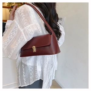 Detail shot of a dark red underarm bag featuring a golden square buckle worn by a model