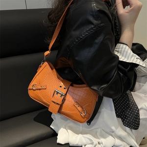 Chic orange crocodile pattern shoulder bag with silver buckle worn by a model