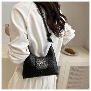 Détail du sac bandoulière tressé noir avec nœud argenté et design de sangle nouée