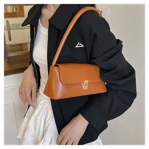 Détail du sac baguette marron avec boucle en métal doré et finition en similicuir lisse