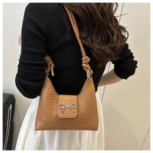 Détail d'un sac demi-lune marron tressé avec fermoir nœud argenté et bandoulière torsadée