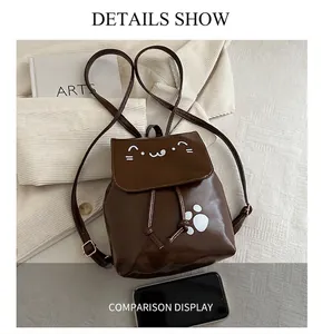 Detailed top view of dark brown cat-themed backpack with white paw print on fabric background