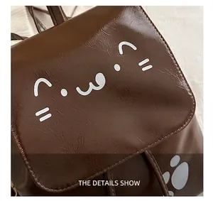 Detail view of brown glossy leather backpack with cute white cat face print and stitching