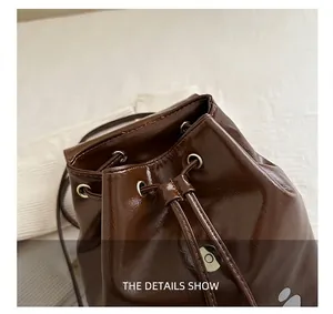 Detail shot of a dark brown drawstring bucket bag in glossy patent leather finish