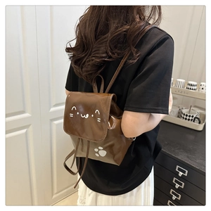 Close-up of small brown PU leather backpack with minimalist cat face and paw print design