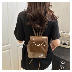 Brown bow mini backpack with cute cat patterns shown on a model in a cozy indoor setting