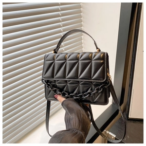 Close-up of black geometric quilted handbag with resin chain and 3D texture