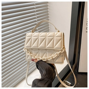 Close-up of beige quilted crossbody bag with chunky chain detail and soft texture