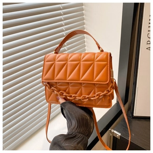 Macro detail of the orange quilted leather crossbody bag with decorative thick chain link