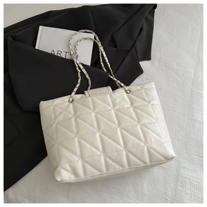 Close-up of cream white quilted tote bag with silver chain strap and metal buckle detail
