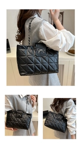 Detail of black quilted tote bag with silver bow accent and leather chain strap