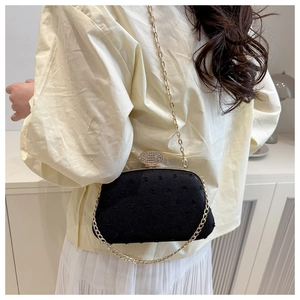 Detail of black textured evening bag with gold chain and sparkling crystal clasp