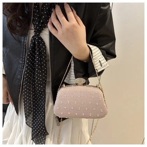 Close-up of pink embroidered crossbody bag with white flower patterns and rhinestone clasp