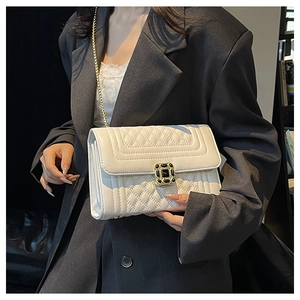 Close-up of white quilted crossbody bag with gold chain strap and black gem lock